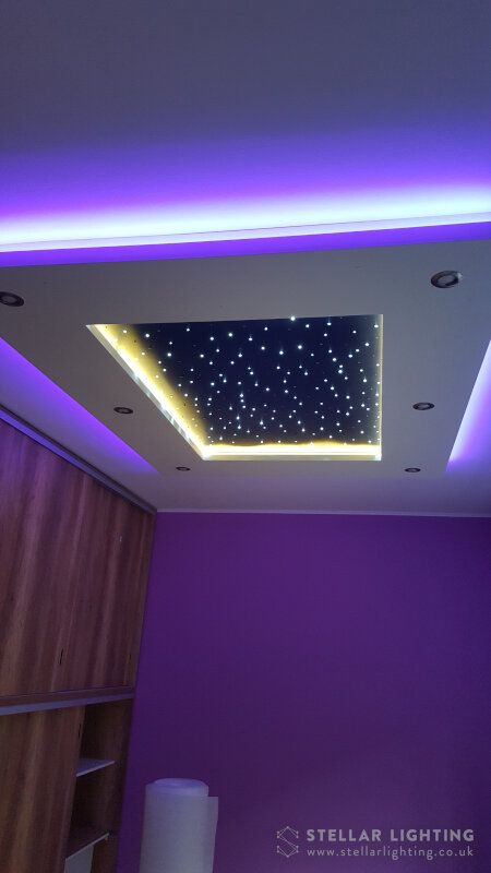 the ceiling is lit up with purple lights and stars on it, as well as some bookshelves