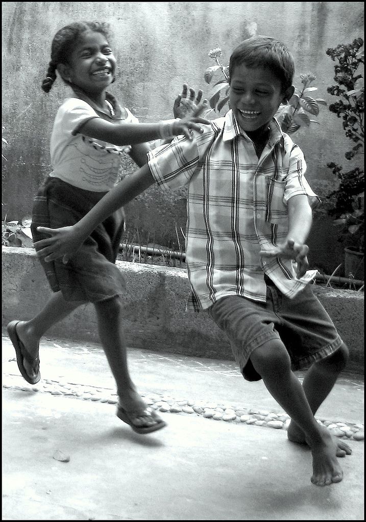 two young children are playing with each other outside in black and white, one boy is holding his hand out to the other