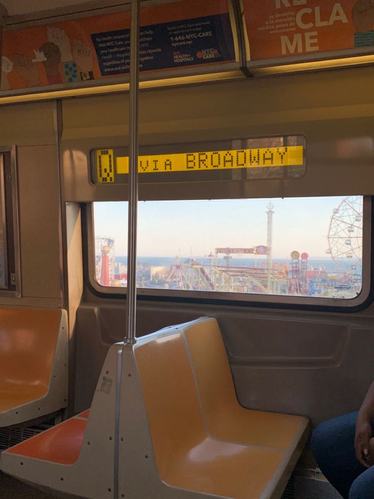 two people sitting on a train looking out the window at an amusement park and ferris wheel