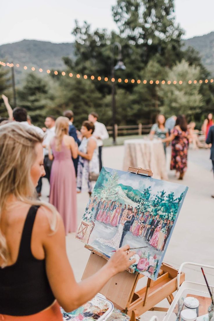 a woman is painting on an easel in front of a group of people outside