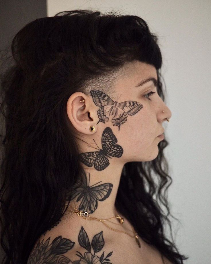 a woman with butterfly tattoos on her neck and shoulder, looking off to the side