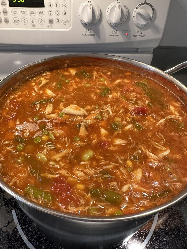 a pot filled with soup sitting on top of a stove next to an electric oven