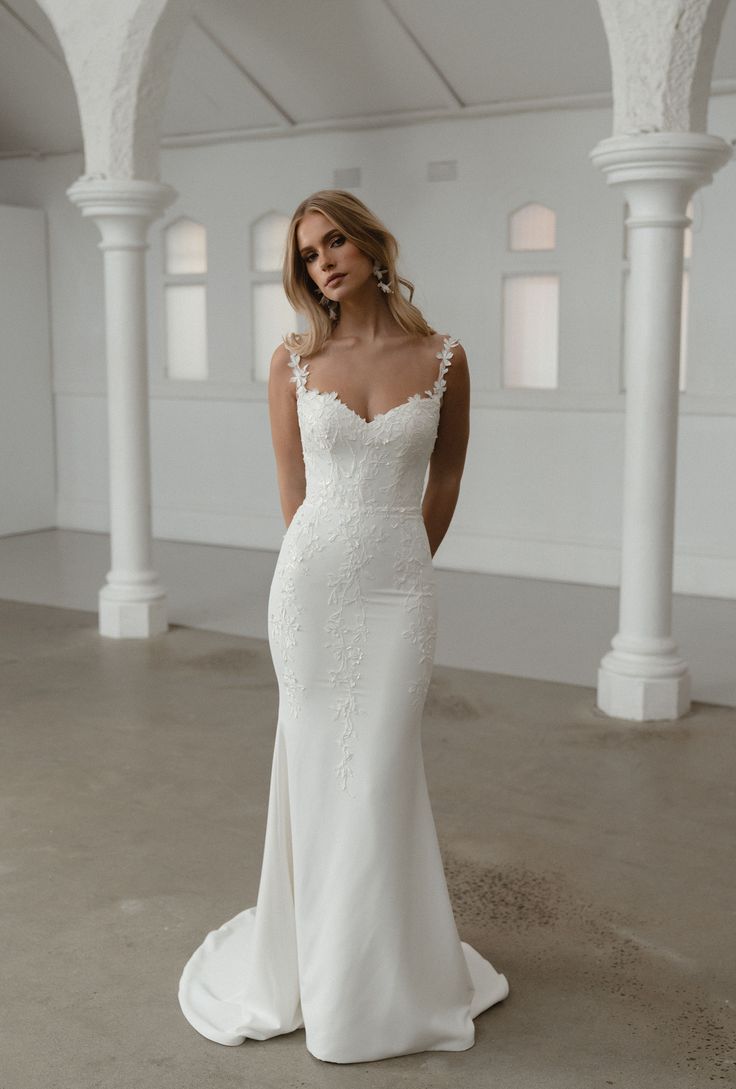 a woman in a white wedding dress posing for the camera with her hands on her hips