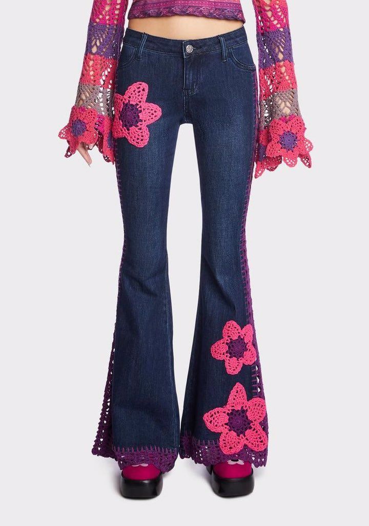 a woman is wearing flarey jeans with pink flowers on the side and bell sleeves