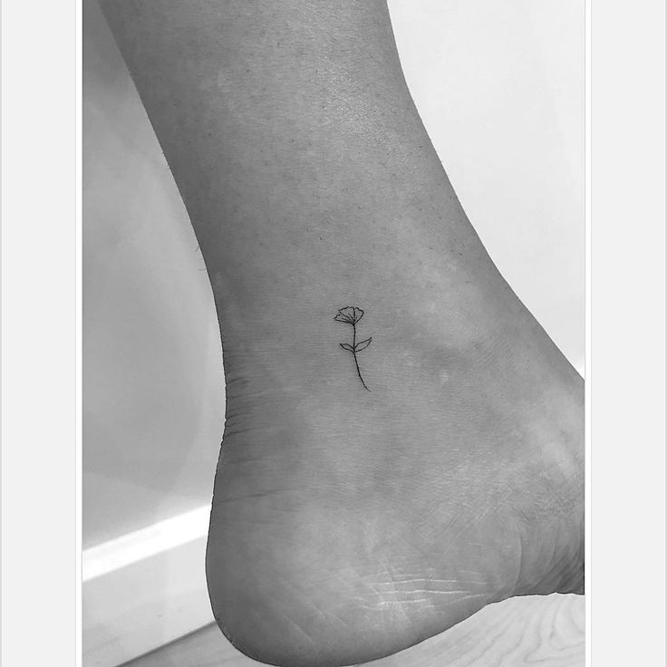 a single flower tattoo on the ankle is seen in this black and white photo,