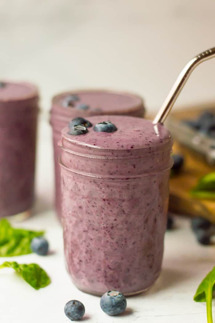 blueberry spinach smoothie in a mason jar with a straw and fresh blueberries on the side