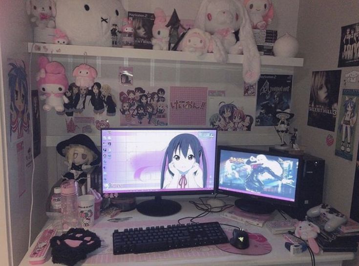 two computer monitors sitting on top of a desk next to stuffed animals and other items