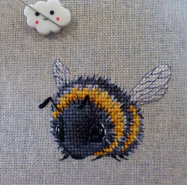 a close up of a piece of fabric with a bee on it next to a needle