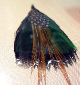 a green and brown feather laying on top of a table