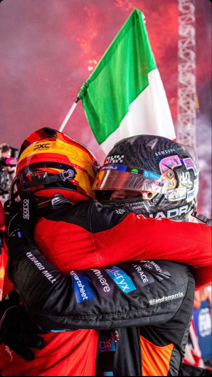 two people hugging each other with a flag in the background