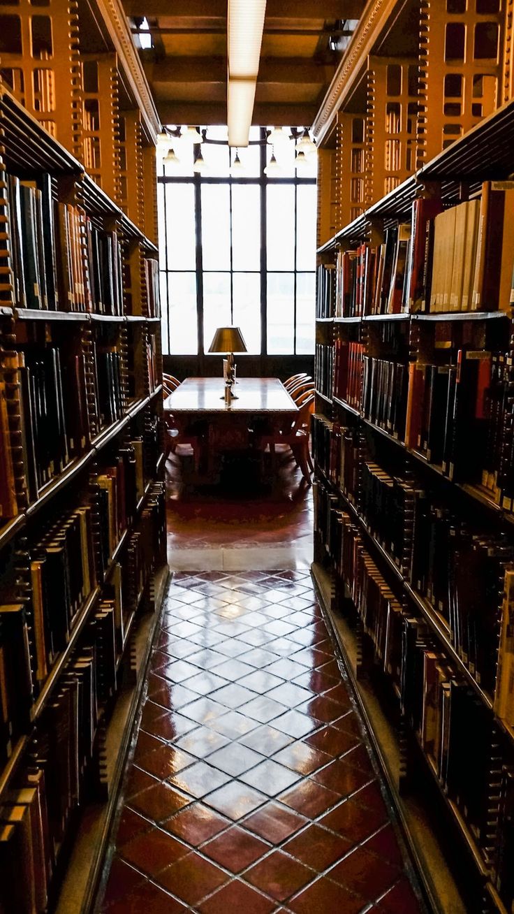 an empty library with lots of books on shelves and a desk in the middle between them