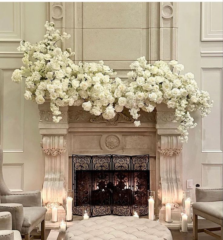 an elegant fireplace with candles and flowers on the mantel, surrounded by white hydrangeas