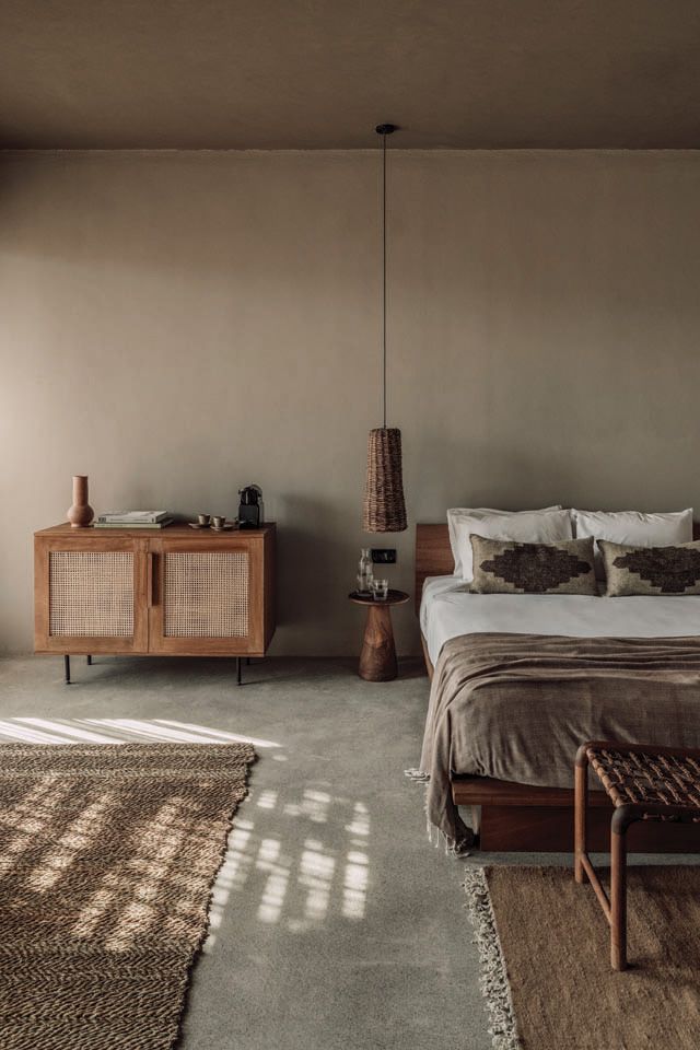 a bed sitting next to a wooden dresser in a bedroom on top of a carpeted floor