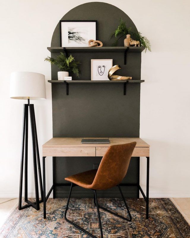 a desk with a lamp and some pictures on the wall above it, along with a chair