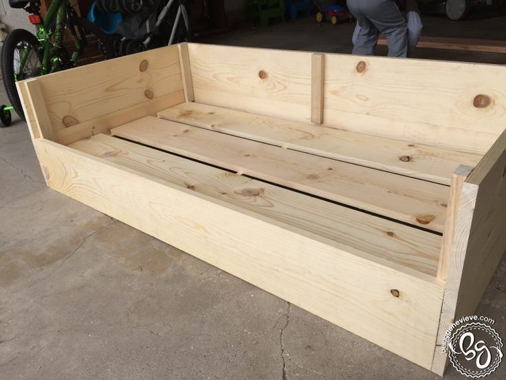 a wooden bench sitting on top of a cement floor next to a bike parked in front of it