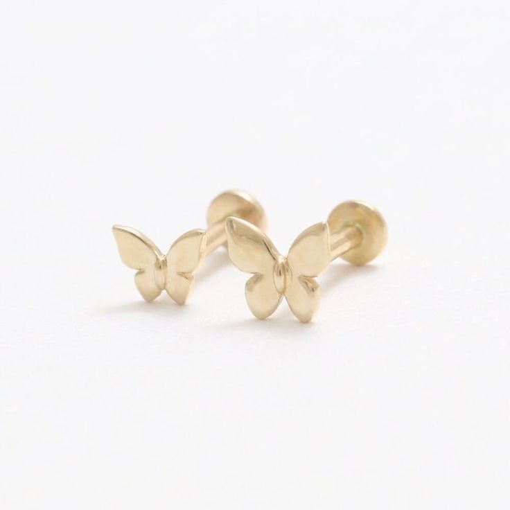 two small gold butterfly studs on white background