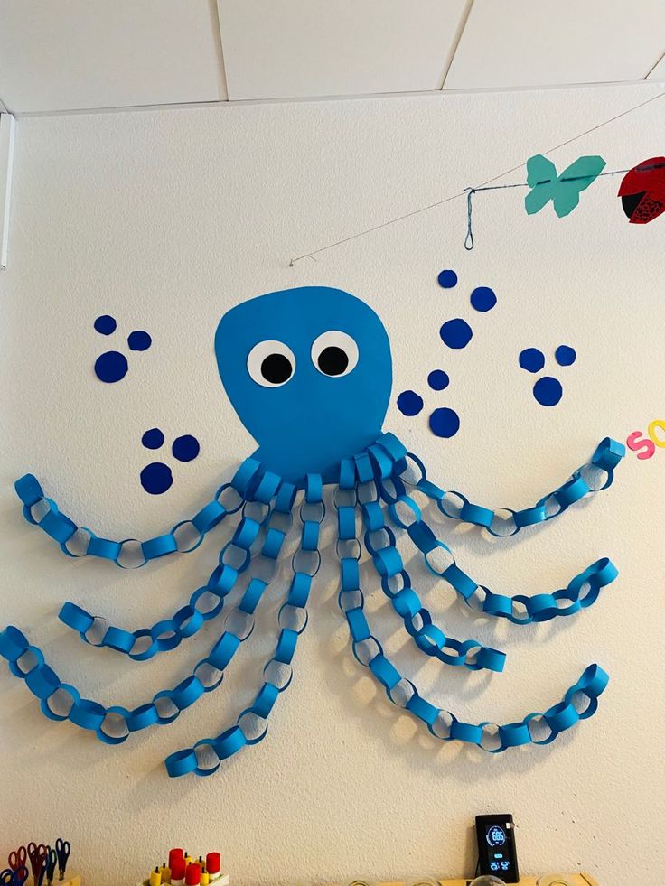 a blue octopus made out of plastic beads on a wall with other toys and decorations