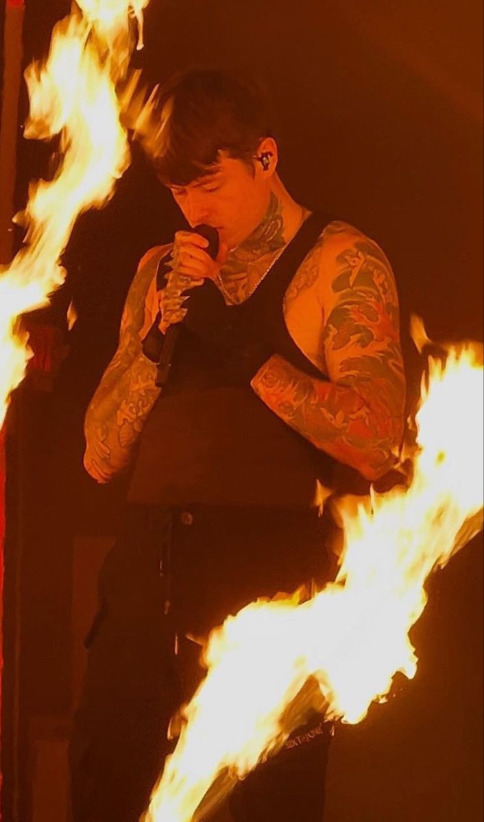 a man standing in front of fire holding a microphone