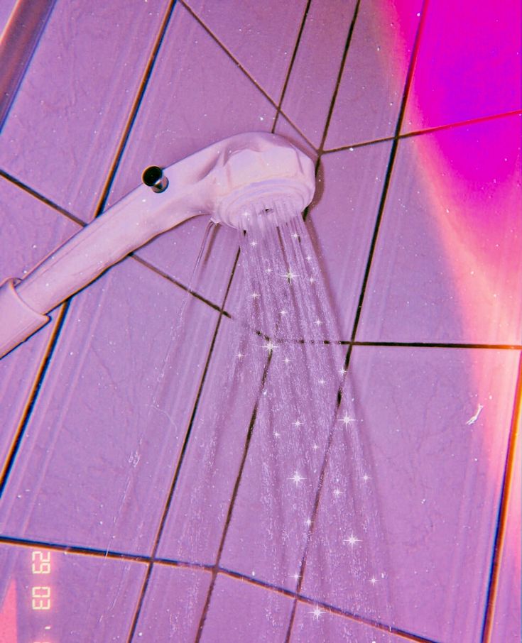 a close up of a shower head on a tiled floor with pink and purple tiles