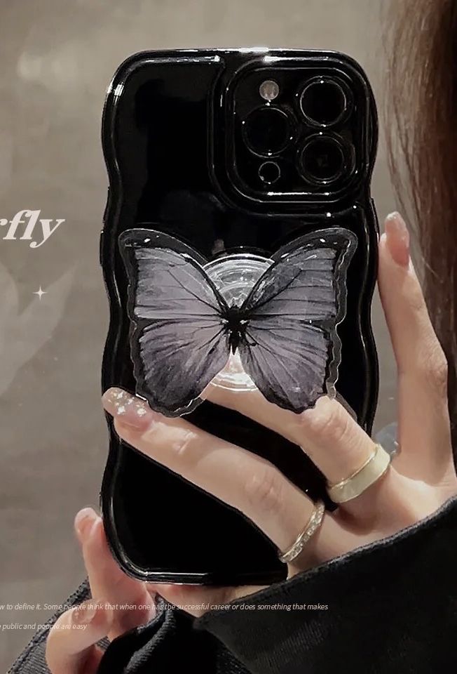 a woman holding up a phone case with a butterfly on it