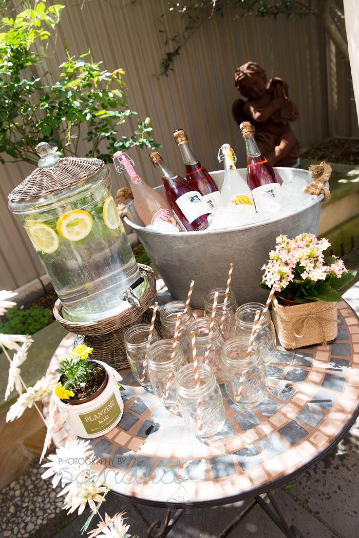 a table topped with lots of bottles of wine and glasses next to a potted plant