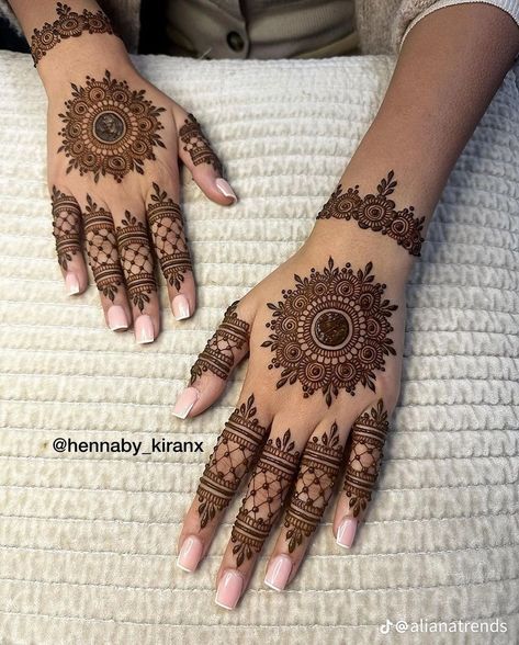 two hands with henna tattoos on them, one is showing off the intricate design