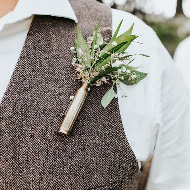 a boutonniere with greenery on it is worn by a man in a vest