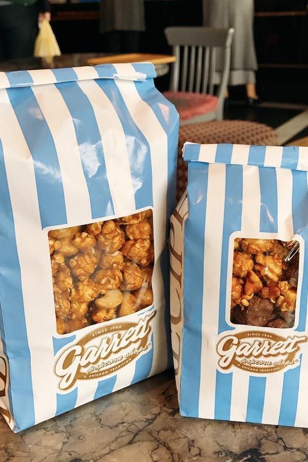 two bags of popcorn sitting on top of a table next to each other in front of a counter