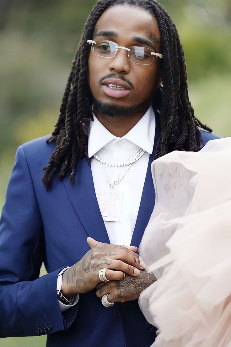 a man with dreadlocks wearing a blue suit and holding a pink tulle