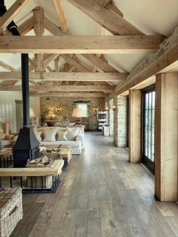 a living room filled with lots of furniture and wooden beams on the ceiling next to windows