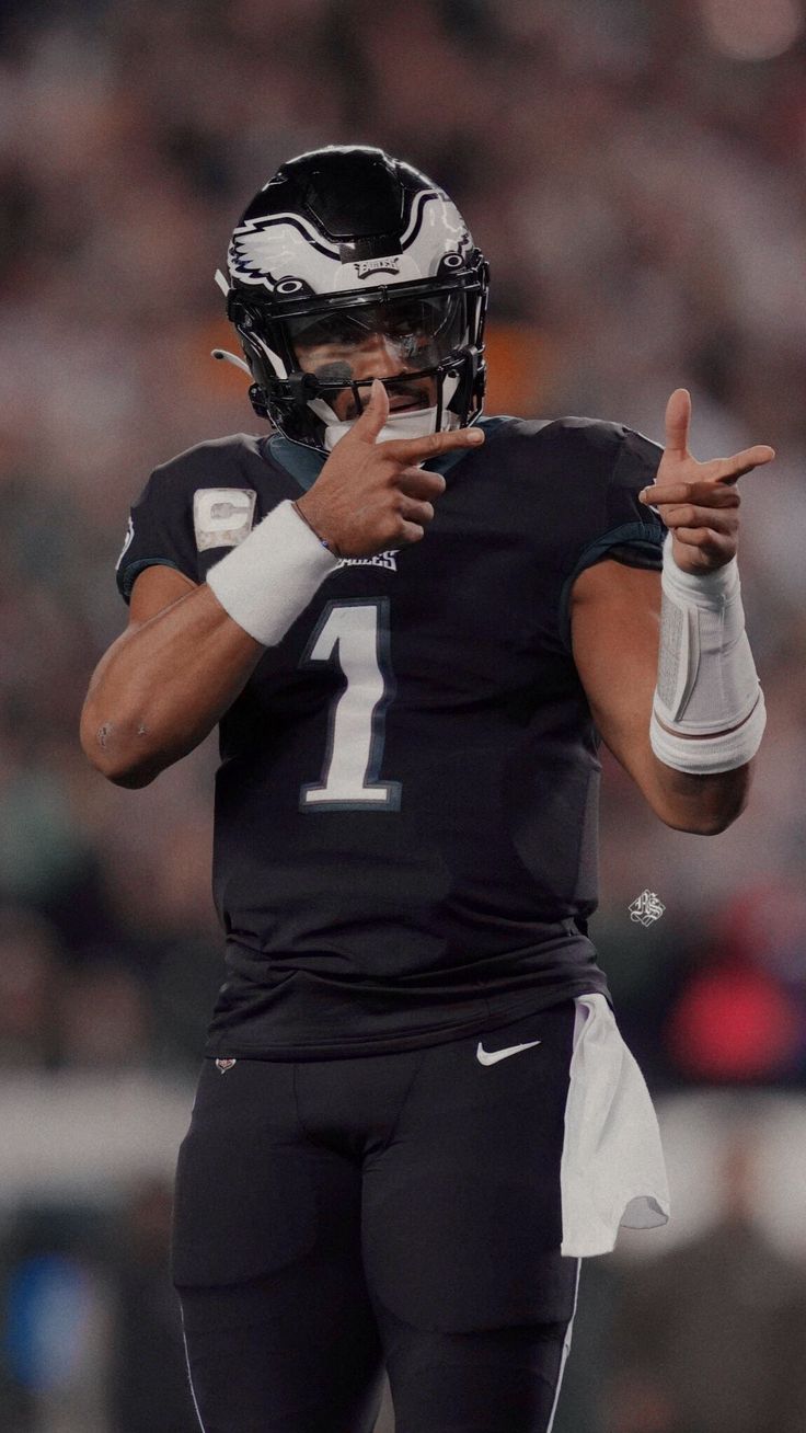 a football player is holding his hand out to the sidelines while wearing a black and white uniform