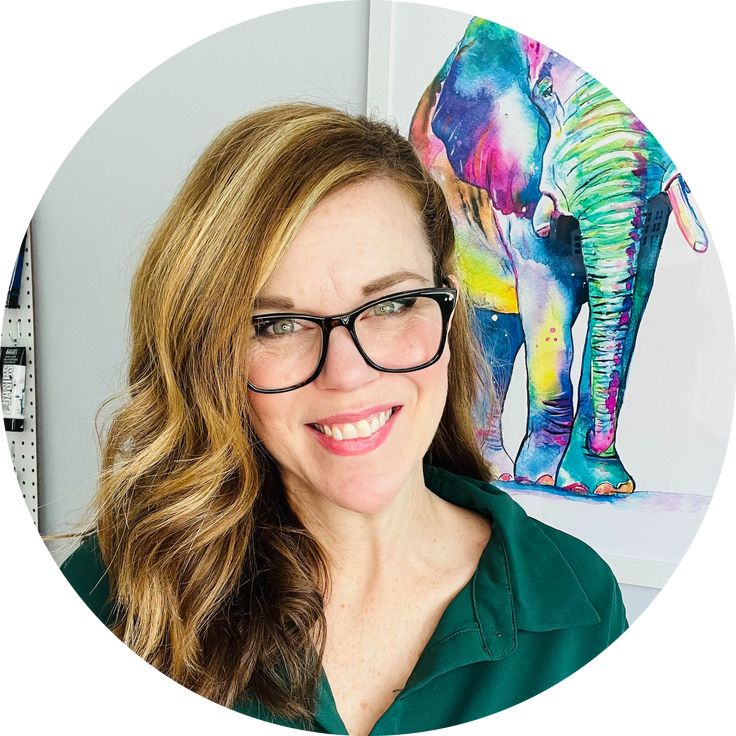 a woman wearing glasses standing in front of an elephant painting