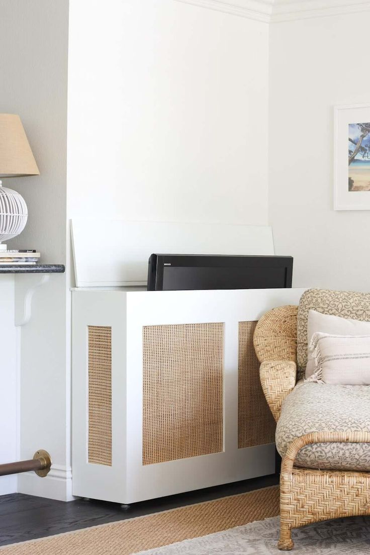 a wicker chair sitting in front of a white cabinet