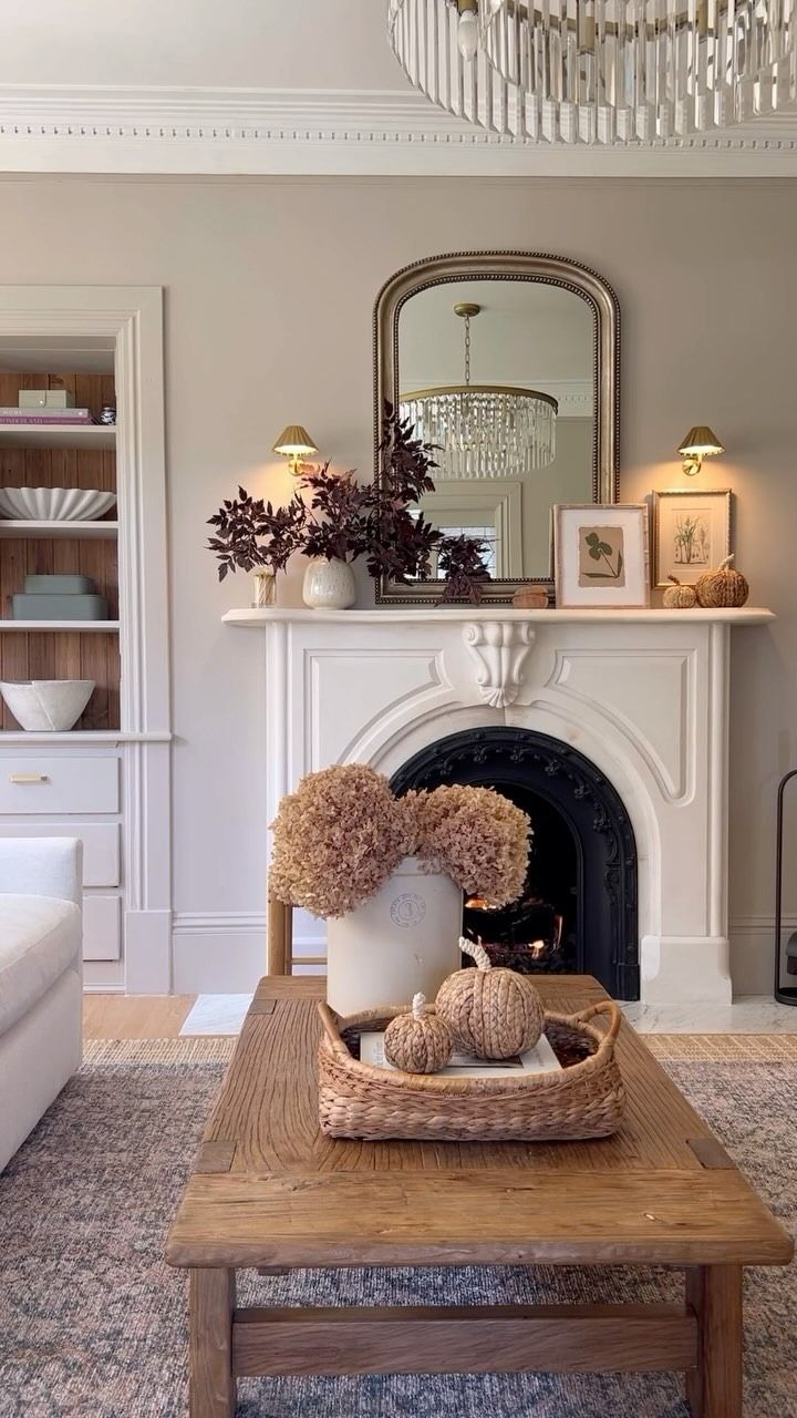 a living room filled with furniture and a fire place under a chandelier on top of a wooden coffee table