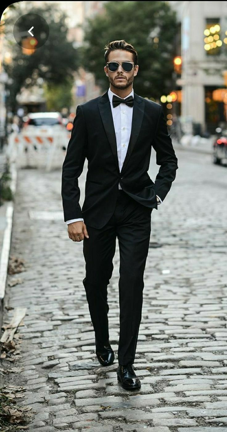 a man in a tuxedo is walking down the street