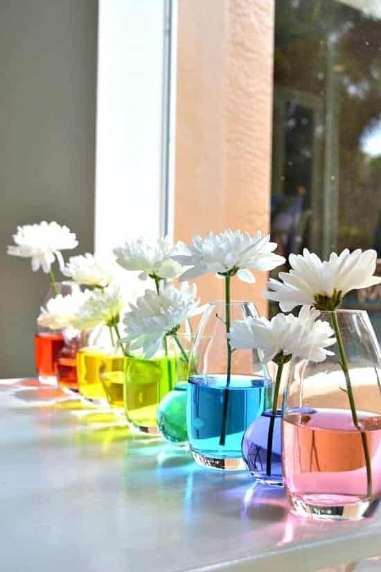 colorful vases filled with flowers sitting on top of a table next to a window