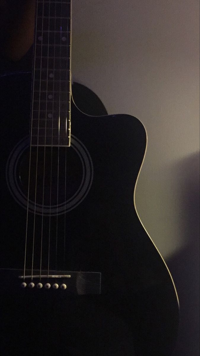 a black acoustic guitar sitting on top of a table