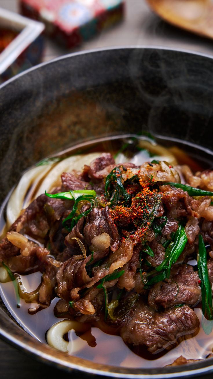 a bowl filled with meat and noodles on top of a table