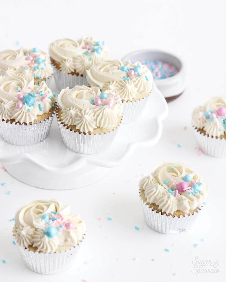 cupcakes with white frosting and sprinkles on a cake platter