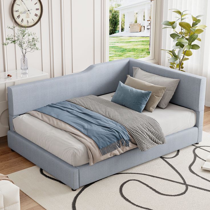 a blue day bed sitting on top of a wooden floor next to a white rug