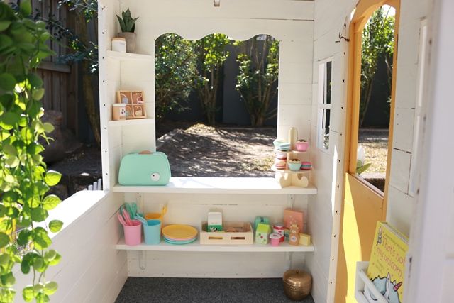 the inside of a toy house with toys on shelves and in front of an open door