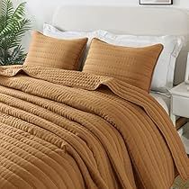 a bed covered in a brown blanket and pillows