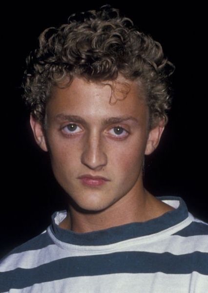 a young man with curly hair wearing a striped shirt