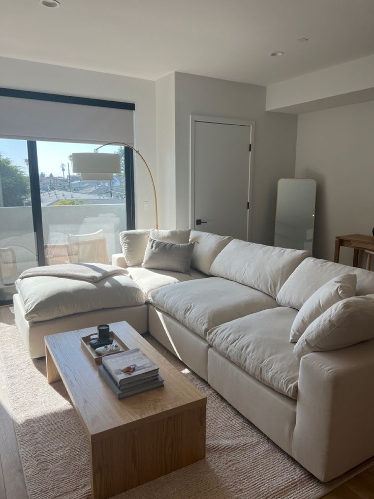 a living room with a large white couch in front of a window and a coffee table