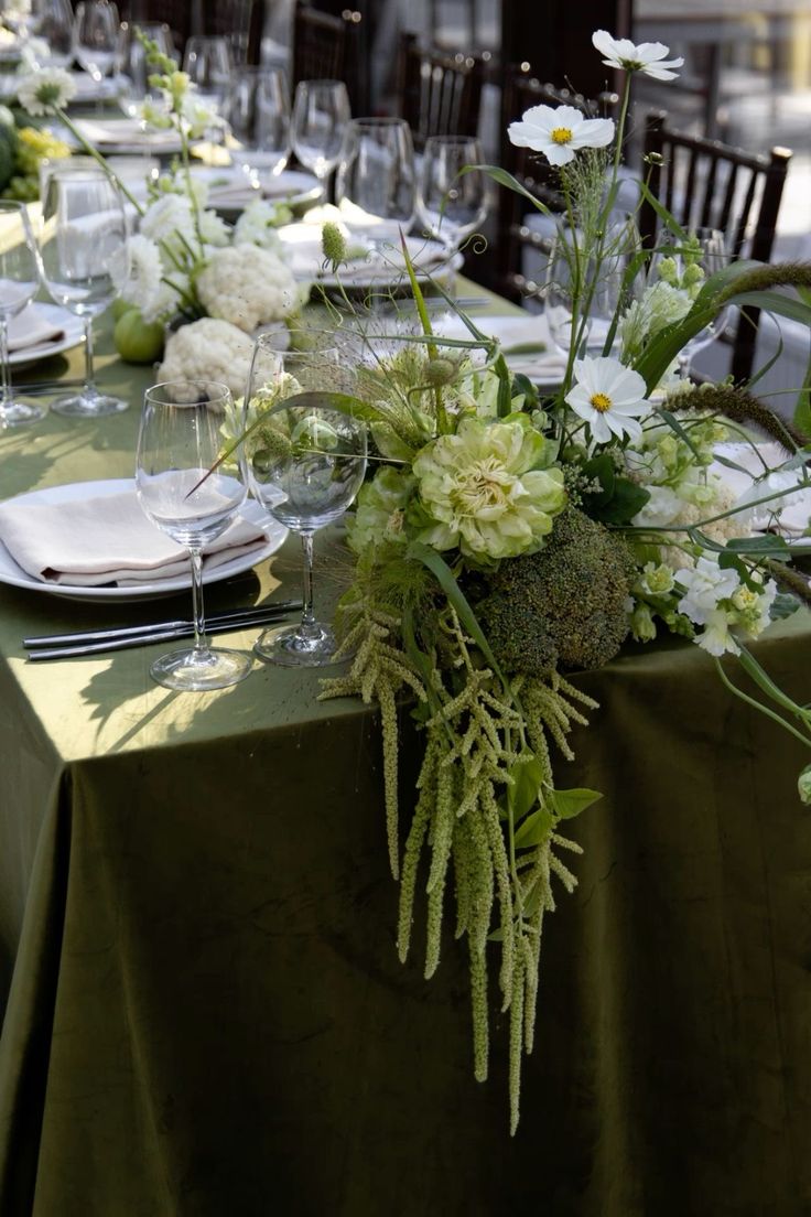 the table is set with white flowers and greenery for an elegant dinner or party