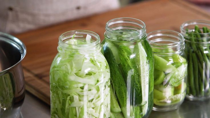 several jars filled with cucumbers and green onions