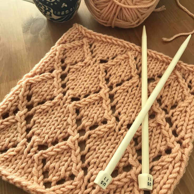 two knitting needles are laying next to a crochet afghan