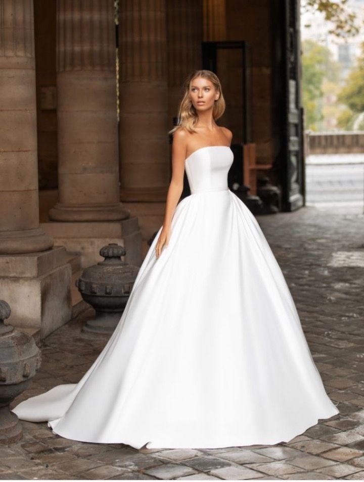 a woman in a white wedding dress standing on a stone floor with columns behind her