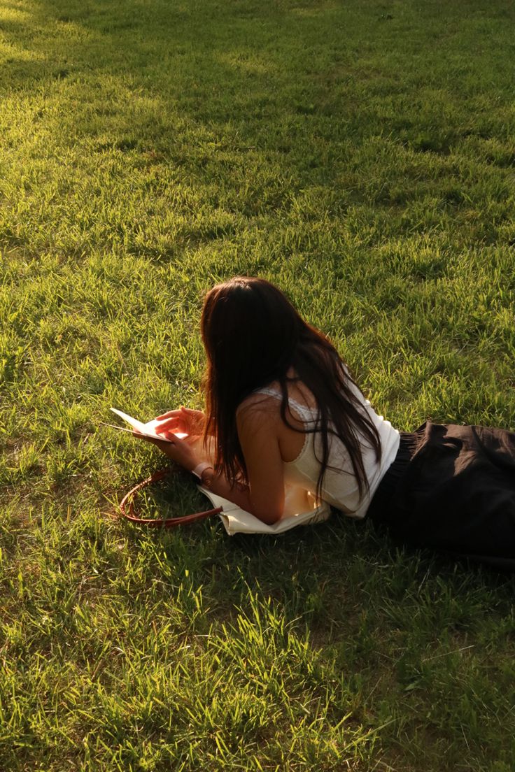 a woman laying on top of a lush green field