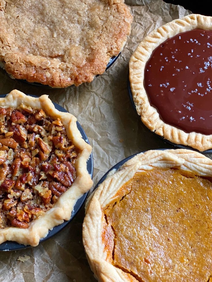 four pies and two tarts sitting on wax paper